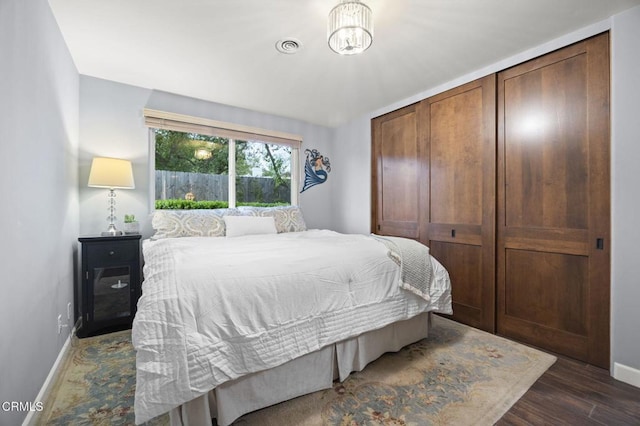 bedroom featuring an inviting chandelier, visible vents, dark wood finished floors, and baseboards