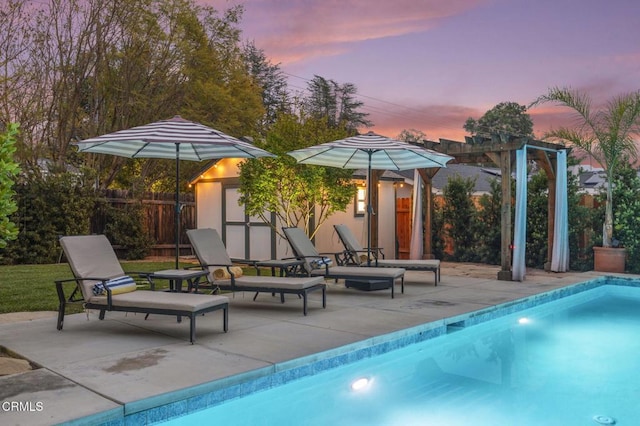 pool at dusk with fence, an outdoor structure, a patio, and a fenced in pool