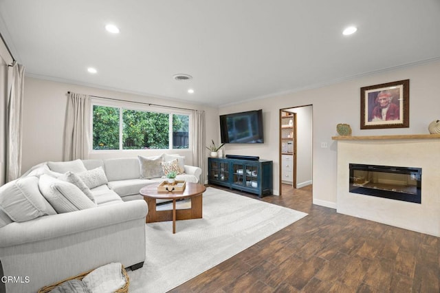 living area featuring a glass covered fireplace, wood finished floors, recessed lighting, and ornamental molding