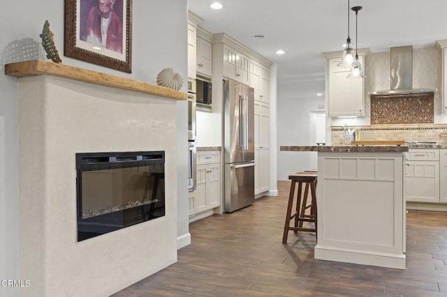 kitchen featuring wall chimney range hood, recessed lighting, high end fridge, and dark wood-style floors