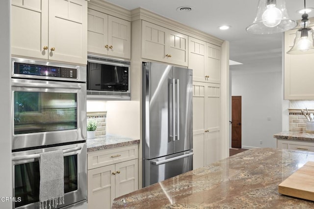 kitchen with pendant lighting, tasteful backsplash, stainless steel appliances, light stone countertops, and recessed lighting
