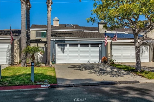 townhome / multi-family property featuring roof mounted solar panels, driveway, a chimney, and roof with shingles