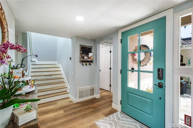 foyer entrance with stairway, wood finished floors, baseboards, visible vents, and recessed lighting