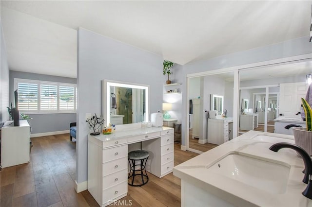 bathroom featuring baseboards, lofted ceiling, vanity, and hardwood / wood-style flooring