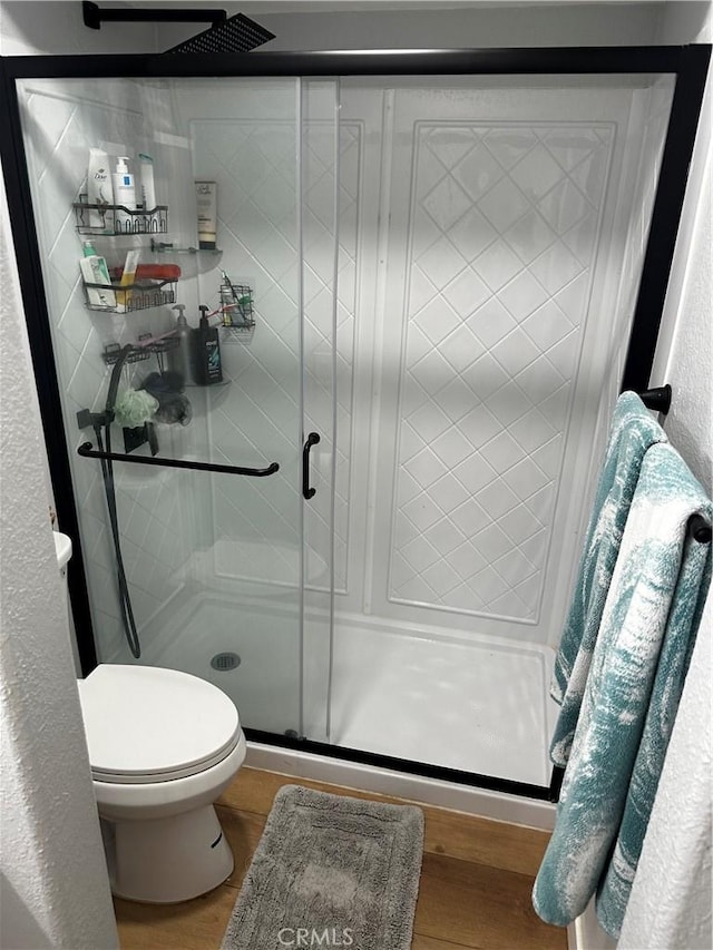 full bath featuring a shower stall, wood finished floors, and toilet