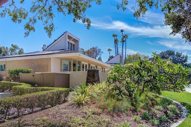 view of side of property with stucco siding and fence