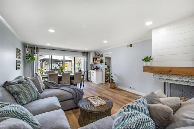 living room featuring recessed lighting, light wood-style flooring, visible vents, and ornamental molding