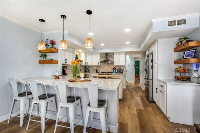 kitchen with a peninsula, visible vents, freestanding refrigerator, wall chimney range hood, and open shelves