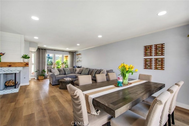 dining area with baseboards, recessed lighting, wood finished floors, crown molding, and a fireplace