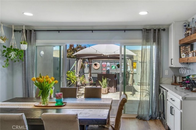 dining space with light wood-type flooring, indoor bar, beverage cooler, and recessed lighting