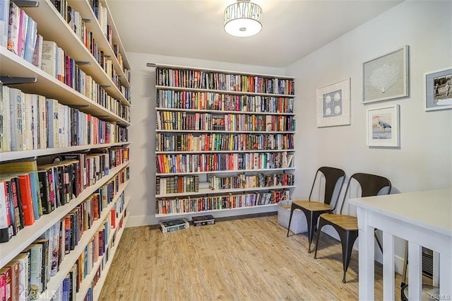 sitting room featuring baseboards, wood finished floors, and bookshelves