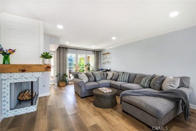living area with a tile fireplace, wood finished floors, recessed lighting, and crown molding