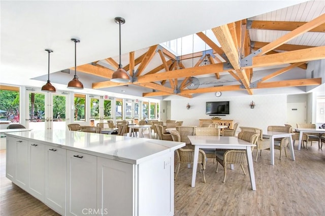 kitchen featuring lofted ceiling with beams, light wood-style floors, light countertops, a kitchen island, and hanging light fixtures