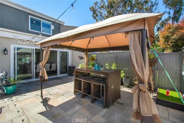 view of patio featuring a gazebo, outdoor dining area, and fence
