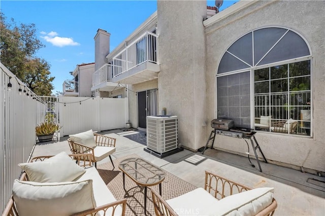 view of patio with a fenced backyard, outdoor lounge area, a balcony, and central AC