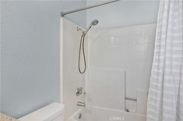 full bathroom featuring shower / bath combo, toilet, and a textured wall