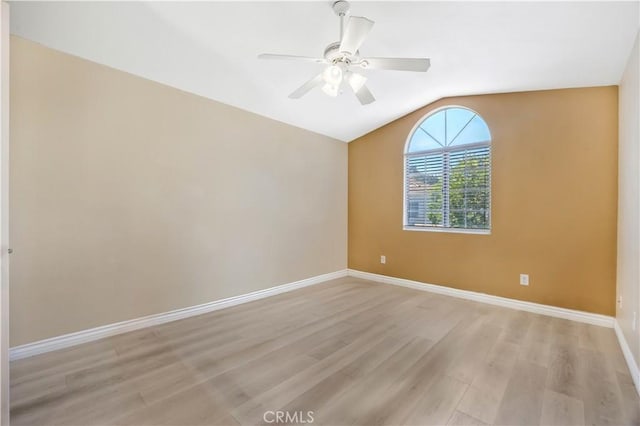 spare room with light wood-type flooring, lofted ceiling, baseboards, and ceiling fan