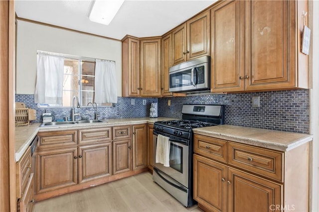 kitchen with brown cabinetry, stainless steel appliances, light countertops, and a sink