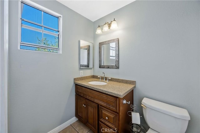 half bath featuring toilet, vanity, tile patterned floors, and baseboards