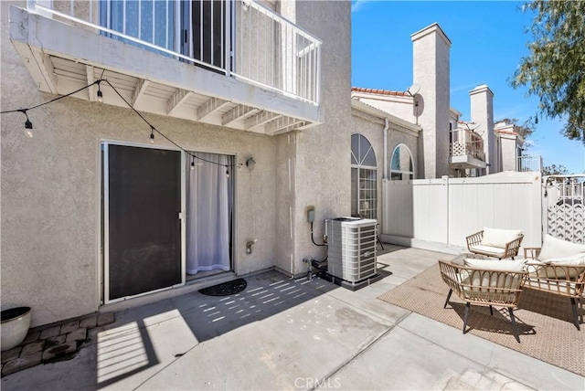 view of patio / terrace featuring cooling unit, fence, and a balcony