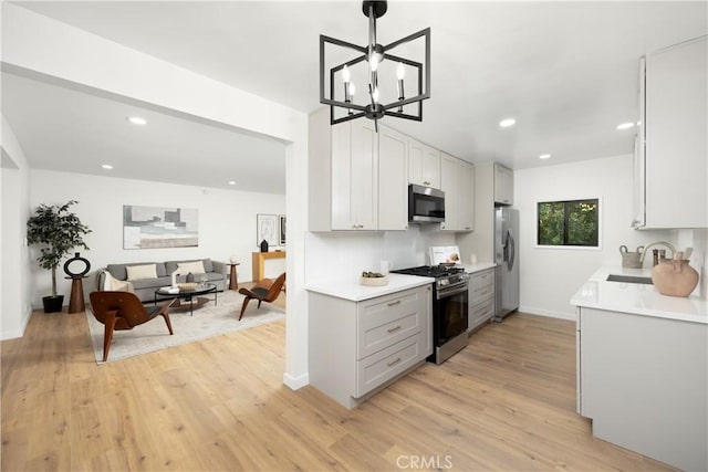 kitchen with a sink, stainless steel appliances, light wood finished floors, light countertops, and recessed lighting