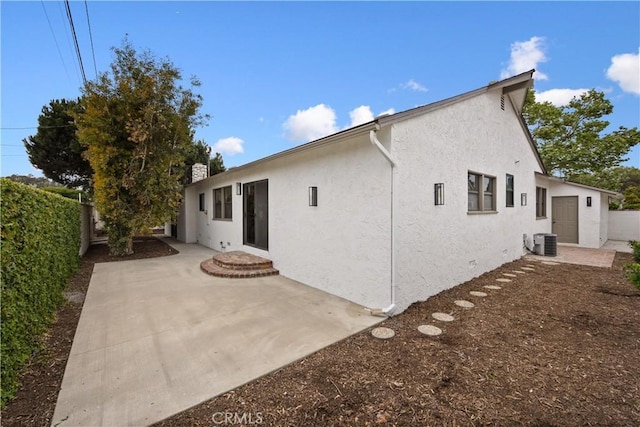 rear view of house with a chimney, a fenced backyard, cooling unit, stucco siding, and a patio area