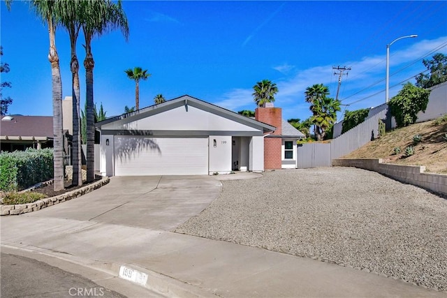 single story home featuring an attached garage, a chimney, concrete driveway, and fence