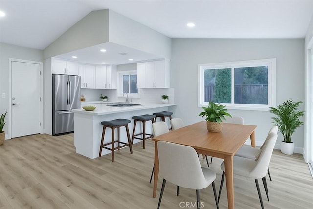 dining room featuring vaulted ceiling, light wood finished floors, and recessed lighting