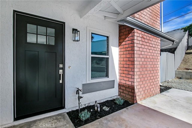 property entrance with brick siding and stucco siding