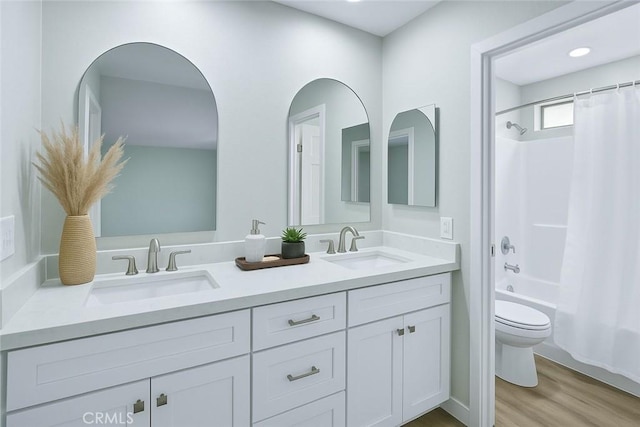 bathroom with shower / tub combo with curtain, a sink, double vanity, and toilet
