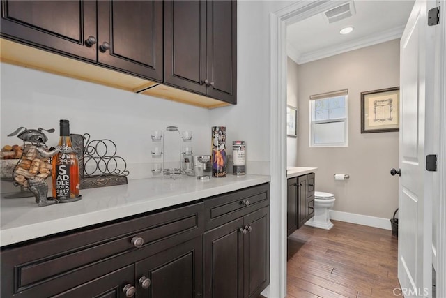 indoor dry bar with crown molding, baseboards, hardwood / wood-style floors, and recessed lighting
