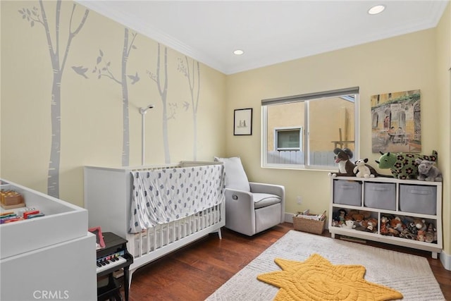 bedroom featuring ornamental molding, a nursery area, wood finished floors, and recessed lighting