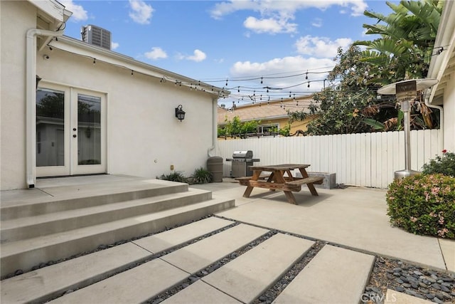 view of patio with french doors, fence, a grill, central AC, and outdoor dining area