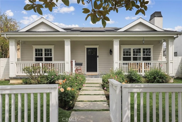 bungalow-style home featuring a porch, a chimney, and solar panels