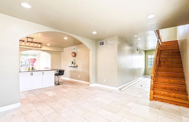 interior space featuring arched walkways, baseboards, visible vents, recessed lighting, and stairway