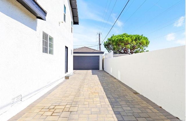 view of side of property featuring fence, a garage, and stucco siding