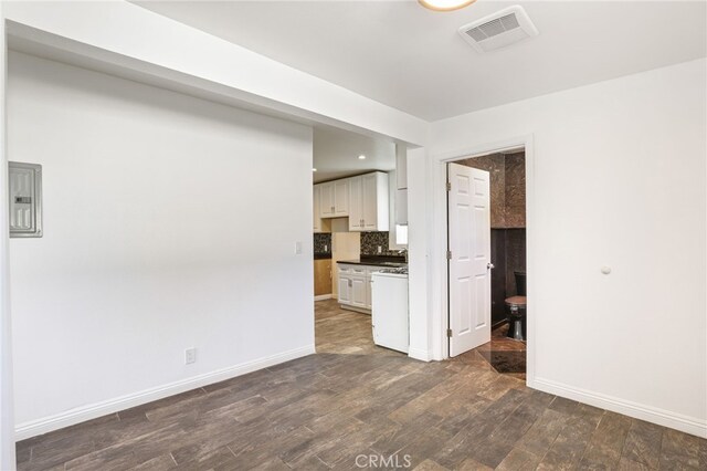 unfurnished living room with baseboards, dark wood-type flooring, and visible vents