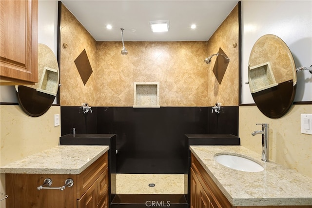 bathroom with recessed lighting, two vanities, walk in shower, and a sink