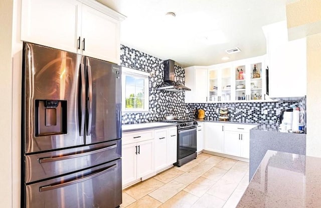 kitchen featuring visible vents, white cabinetry, range with gas stovetop, wall chimney range hood, and stainless steel fridge with ice dispenser