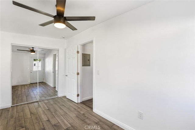 unfurnished room featuring wood finished floors, electric panel, baseboards, and ceiling fan