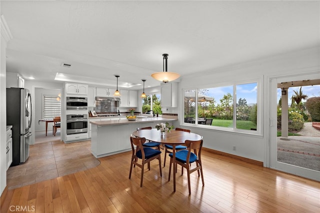 dining area featuring light wood finished floors, visible vents, crown molding, and baseboards