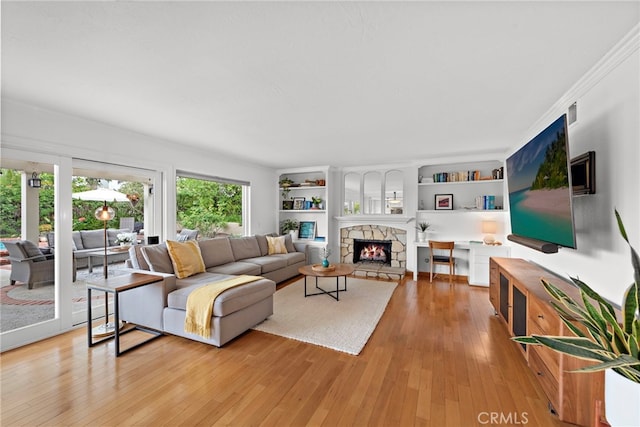 living room featuring built in features, a fireplace, and light wood-style floors