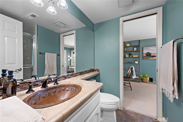 full bathroom with vanity, toilet, a shower with door, and visible vents