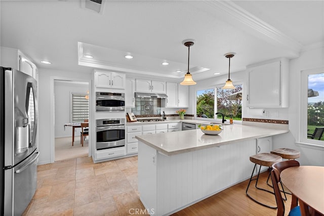 kitchen with crown molding, a sink, appliances with stainless steel finishes, a peninsula, and under cabinet range hood
