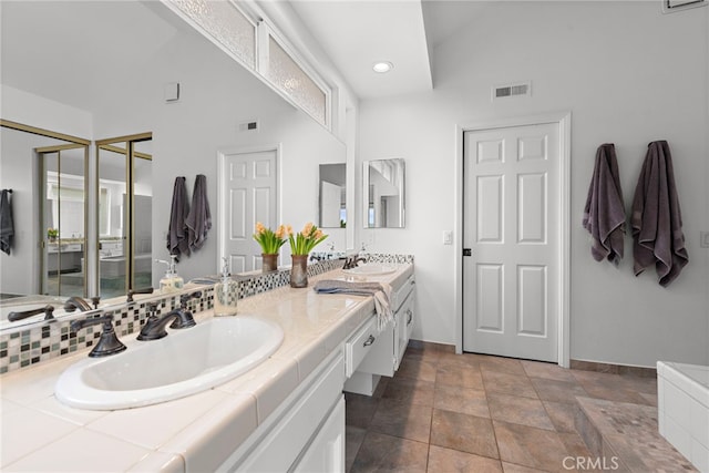 bathroom featuring baseboards, visible vents, a sink, and double vanity