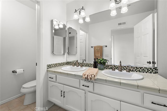 full bath with double vanity, tile patterned floors, toilet, and a sink