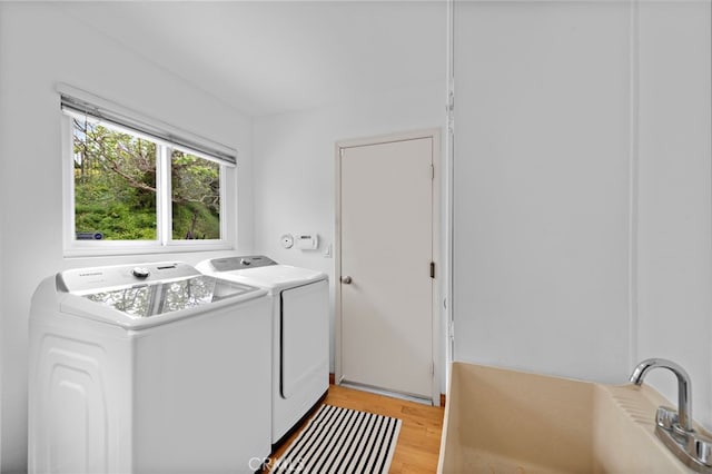 laundry area with washing machine and clothes dryer, light wood-style floors, laundry area, and a sink