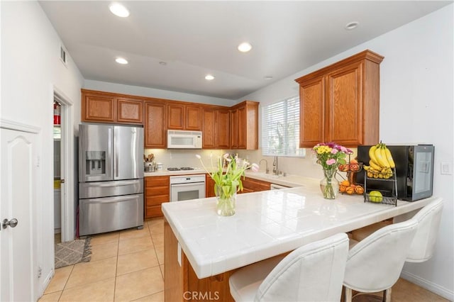 6651 Darling Ln, San Bernardino, CA 92407 - kitchen with brown cabinetry, white appliances, a peninsula, and recessed lighting