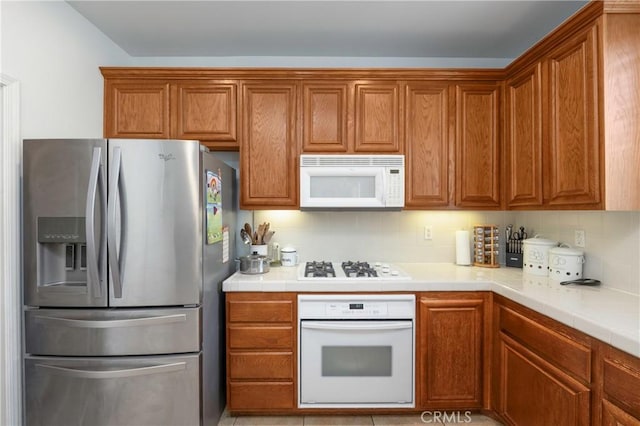 6651 Darling Ln, San Bernardino, CA 92407 - kitchen featuring brown cabinets, white appliances, tile countertops, and tasteful backsplash