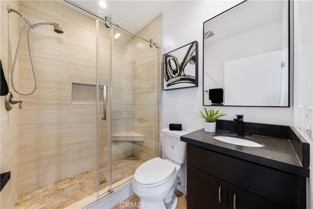 bathroom with toilet, a shower stall, and vanity